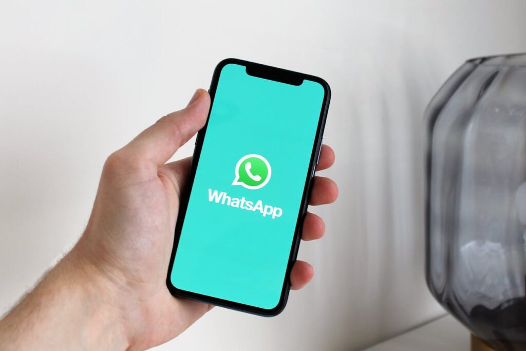 A Hand Holding a Cellphone with a WhatsApp Logo on the Screen
