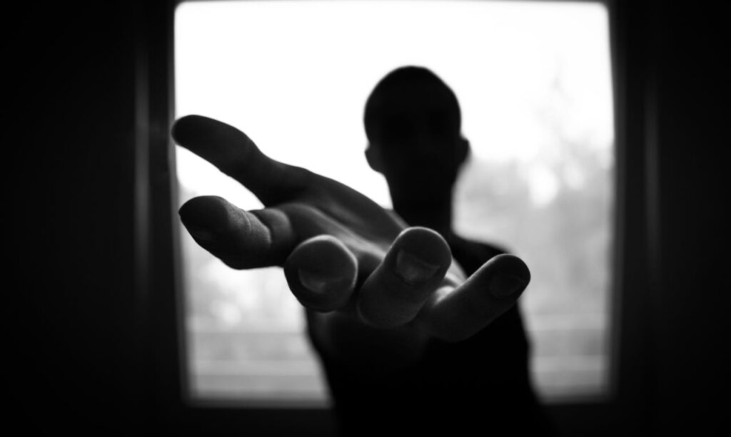 Man's Hand reaching out in Shallow Focus and Grayscale Photography